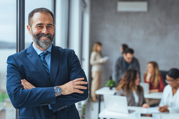Successful business man smiling in a creative office. Portrait of happy mature man looking at...