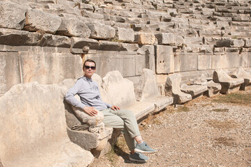 Tourist woman sitting on the steps of The ancient Greek amphitheater at the ancient City in Turkey