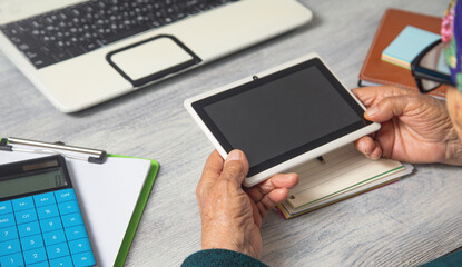 Caucasian elderly woman using digital tablet.