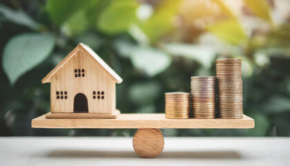  Wooden house model and stack of coins balanced on a wood scale, symbolizing property investment, financial balance, and the comparison between home value and money