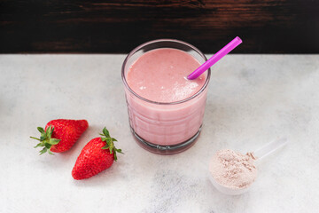 Strawberry smoothie, protein drink in a glass, measuring scoop with whey protein powder, blended cocktail, milkshake