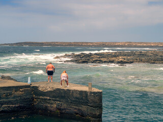 Couple fishing on the shore of a pier