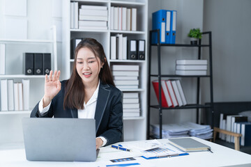 Sharing good business news. Attractive young businesswoman talking on the mobile phone and smiling while sitting at her working place in office and looking at laptop PC.