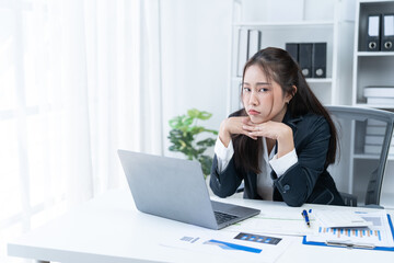 Sharing good business news. Attractive young businesswoman talking on the mobile phone and smiling while sitting at her working place in office and looking at laptop PC.