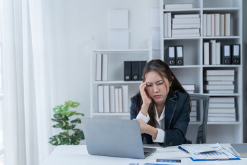 Sharing good business news. Attractive young businesswoman talking on the mobile phone and smiling while sitting at her working place in office and looking at laptop PC.