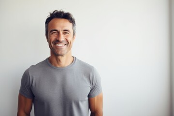 Obraz premium Portrait of a smiling man in his 40s smiling at the camera while standing against minimalist or empty room background