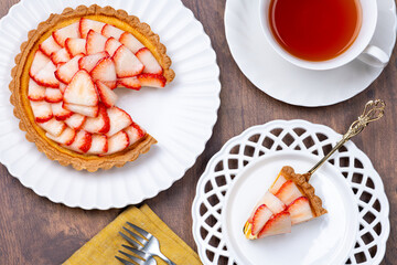 テーブルに並べられたカットした苺のタルトと紅茶の俯瞰