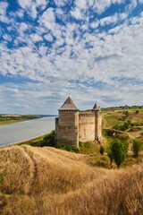 Fototapeta premium Khotyn fortress built in the 14th century. View of top of the fortress wall and towers among the hills closeup on background of Dniester river and its left bank at early springtime
