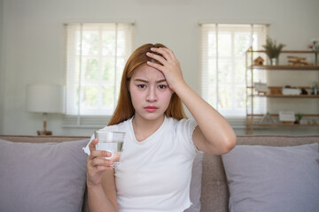 A young Asian woman in the living room was suffering from a headache due to accumulated stress due...