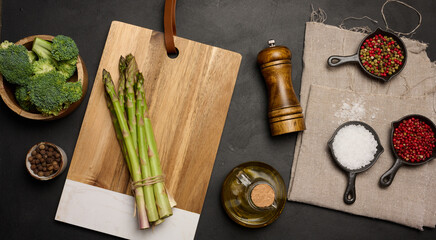 Fresh green asparagus sprouts on a black wooden background. View from above