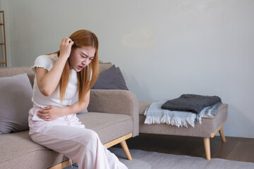 A young Asian woman with abdominal pain from diarrhea or menstrual cramps felt sick and touched her...