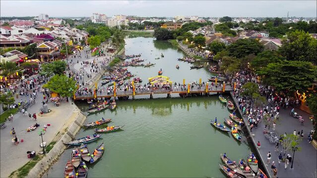 4K Aerial of Hoian, Vietnam. An Hoi Bridge. Night Time. Wide Stationary whilst tourist boats move around the river