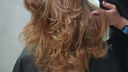 Close-up of a woman's hair being straightened by the hands of a hairdresser. Beauty procedures, a beautiful female hairstyle in a hair salon. High quality 4k footage