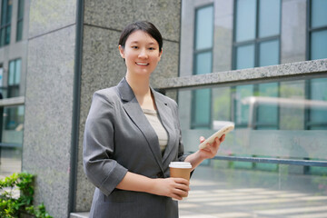 Confident Businesswoman with Coffee and Smartphone Outdoors