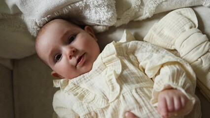Top view of baby girl looking at camera and laughing. Mom tickles laughing baby.