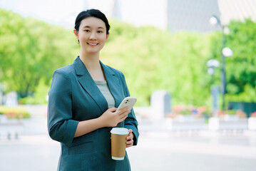 Confident Businesswoman with Smartphone and Coffee Outdoors