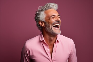 Fototapeta premium Portrait of a content man in his 50s laughing isolated on solid color backdrop
