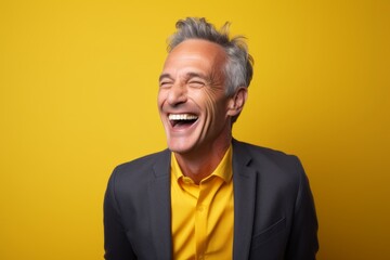 Fototapeta premium Portrait of a content man in his 50s laughing while standing against solid color backdrop