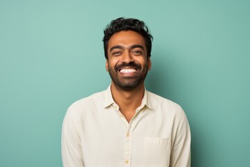 Obraz premium Portrait of a smiling indian man in his 30s smiling at the camera in solid pastel color wall