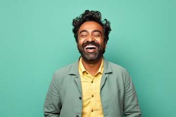 Portrait of a joyful indian man in his 30s showing a thumb up isolated in solid pastel color wall