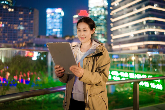 Businesswoman Working on Tablet in City at Night