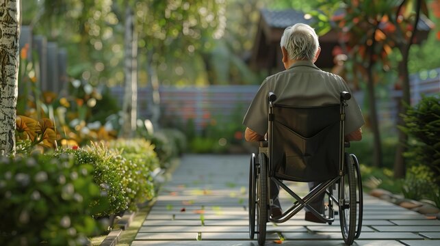 Elder man sitting in a wheelchair and gazing at the garden