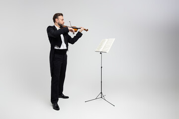 Violinist virtuoso in tuxedo performs melody on classical violin