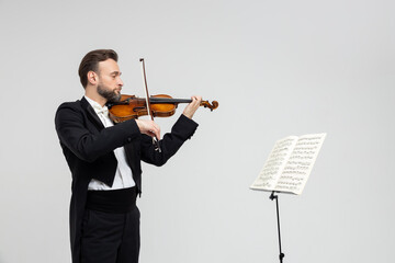 Bearded male violinist playing violin in front of sheet music