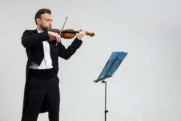 Violinist virtuoso in tuxedo performs melody on classical violin