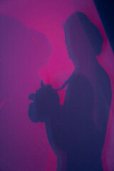 Abstract gradient pink and purple background with the shadow of a woman photographer. Background...