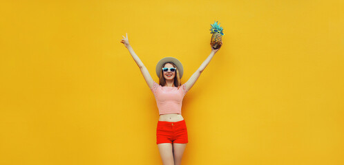 Summer cheerful young woman having fun holding pineapple, emotional girl raising her hands up