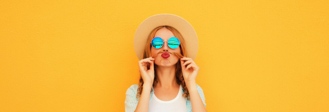 Portrait of funny young woman showing mustache her hair blowing lips wearing summer straw hat