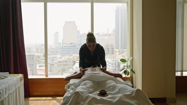 Woman masseuse in a luxury spa center does oil upper body massage to a young tanned client. Female wellness center employee performs a relaxing body care procedure to a girl, releases trigger points