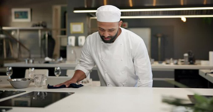 Chef, cloth and cleaning on table in kitchen for maintenance, food safety and disinfection. Hospitality, hygiene and man with fabric at restaurant for compliance, bacteria removal and sanitation