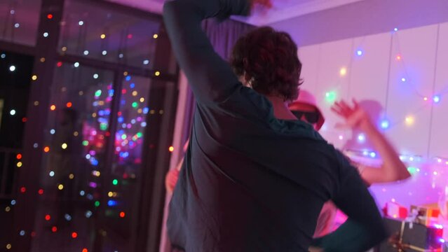 Energetic dancing of three student friends dancing in black glasses in disco gay party room decorated with garlands, cheerful holiday atmosphere, slow motion, holiday background.