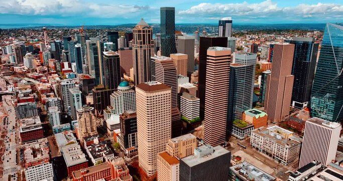 Flying closer to the beautiful modern high-rise buildings in the downtown of Seattle, Washington, US. Sunny cityscape of the metropolis from top.