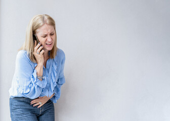A blonde woman is calling her doctor because she is suffering an appendix pain.