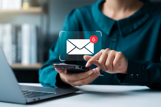 Reminder for unread emails: A businesswoman holds a mobile phone and taps on a new email notification icon. Internet technology.