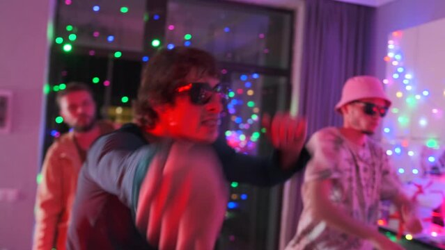 Insane energy as students let loose, moving to music at epic neon lights party indoors. Close up.