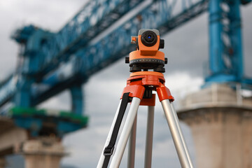 optical level on a cloudy day against the background of huge crane construction.Surveyor's work...
