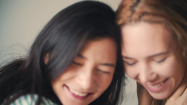 Homosexual lesbian couple lying in bed together. Take hands and smile each other with love. Family, woman love and romantic relationship. Beautiful asian girlfriend in morning home. LGBT pride event.