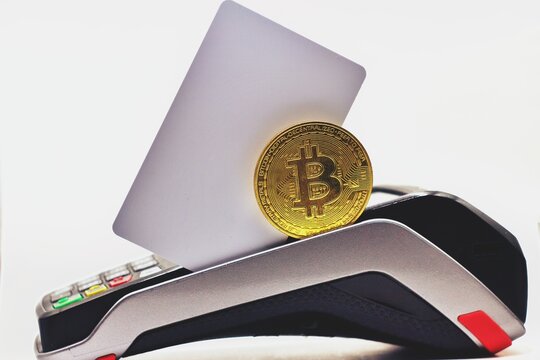 Golden Bitcoin with Credit card reader on the table. Card over a pos terminal credit visa card reader with a mockup