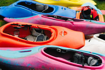 Colorful Stacked Kayaks on Grass Close-Up with Paddles
