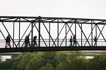 People Crossing an Industrial Metal Bridge