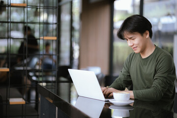A young Asian man works at a coffee shop during the weekend.