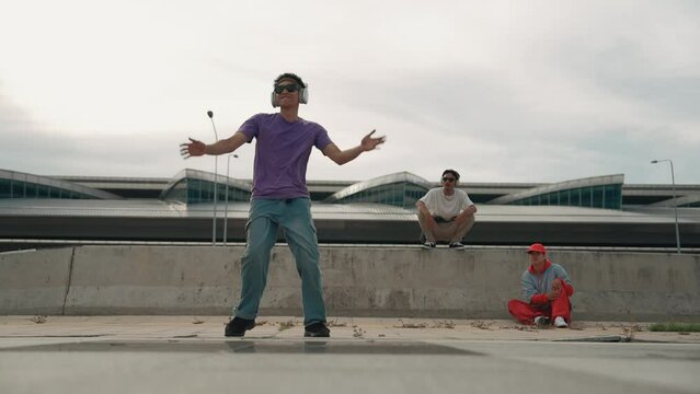 Group of asian break dancer perform street dance with multicultural friend support and moving hip hop music. Attractive handsome hipster practice b boy dance at street. Outdoor sport 2024. Sprightly.