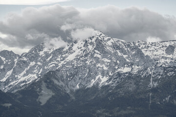 The view depicts a mountain towering over a valley, with lush greenery contrasting the rugged terrain.