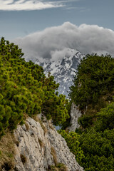 The view depicts a mountain towering over a valley, with lush greenery contrasting the rugged terrain.