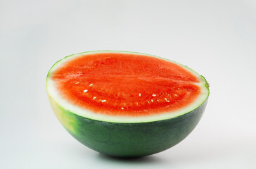 Half a freshly cut watermelon, juicy and red, with a few seeds, on a plain background.