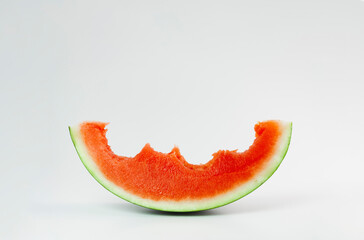 A sweet slice of red watermelon, with bites, seedless, on a smooth background